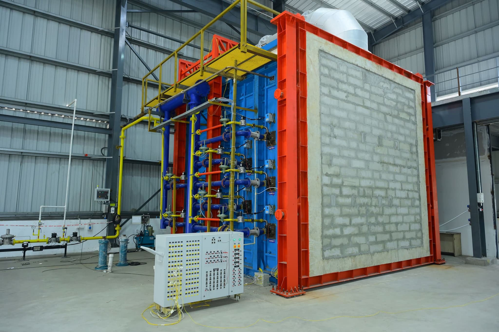 Vertical fire resistance test furnace with a masonry specimen wall mounted in the red specimen frame